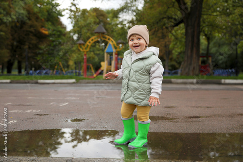 Cute little girl standing in puddle outdoors