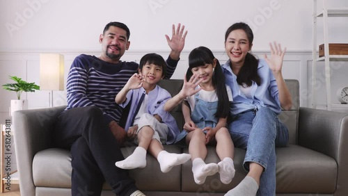 Happy asian family is smiling at the camera.Smiling and waving hello goodbye greetings posing in cozy living room