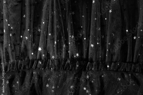 Beautiful black tulle fabric with shiny stars as background, closeup