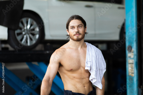 Portrait of a Asian mechanic holding wrench in hand working in his car service garage. Car maintenance and auto service garage concept.