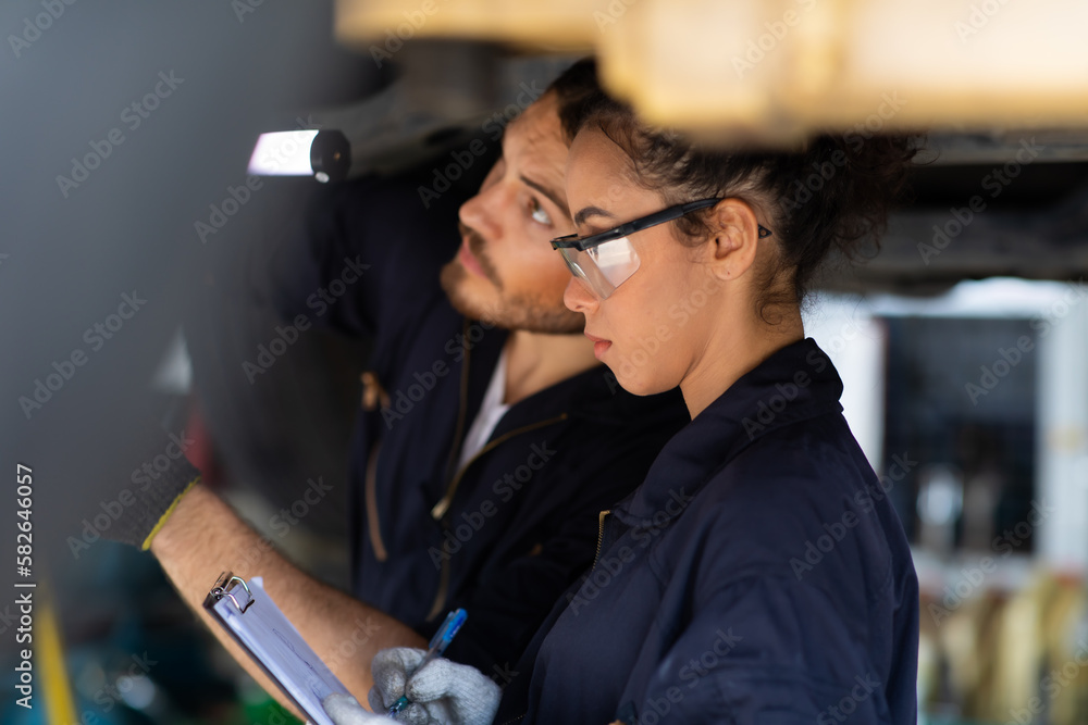 Hispanic Female trainee Mechanics Working Underneath Car Together Car maintenance and auto service garage. Car maintenance and auto service garage concept.