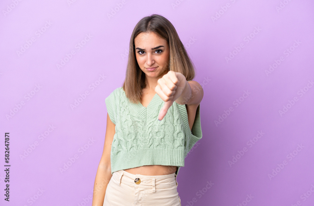 Young caucasian woman isolated on purple background showing thumb down with negative expression Young caucasian woman isolated on purple background showing thumb down with negative expression