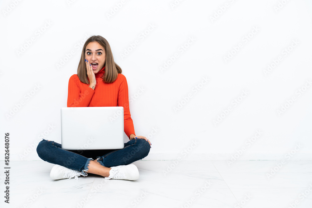 Young caucasian woman sitting on the floor with a laptop with surprise and shocked facial expression Young caucasian woman sitting on the floor with a laptop with surprise and shocked facial expression