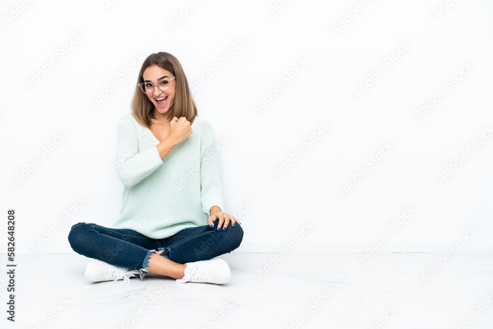 Young caucasian woman sitting on the floor isolated on white background celebrating a victory Young caucasian woman sitting on the floor isolated on white background celebrating a victory