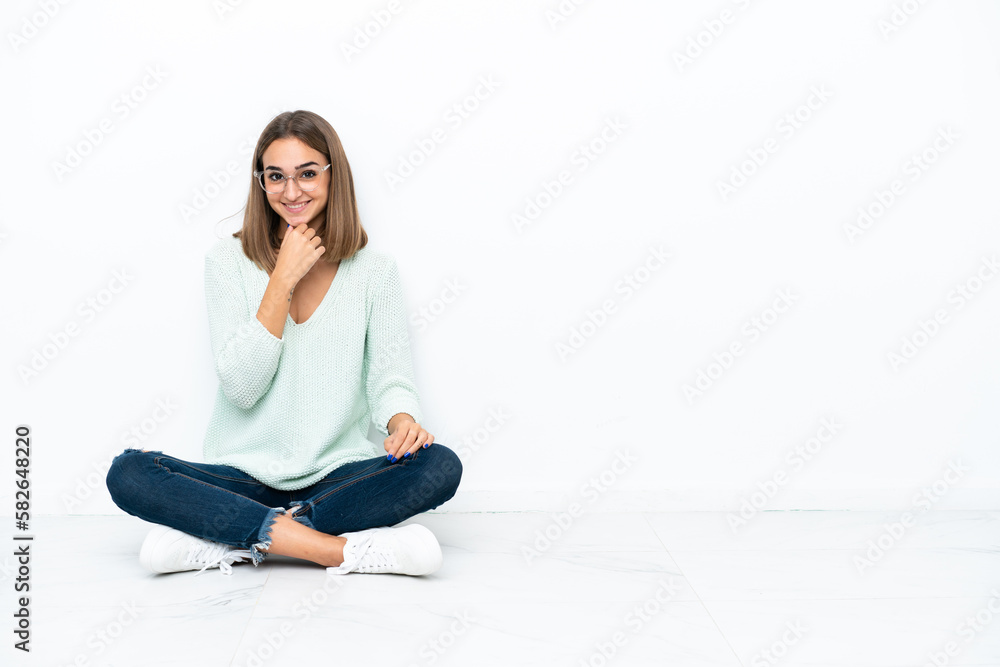 Young caucasian woman sitting on the floor isolated on white background with glasses and smiling Young caucasian woman sitting on the floor isolated on white background with glasses and smiling