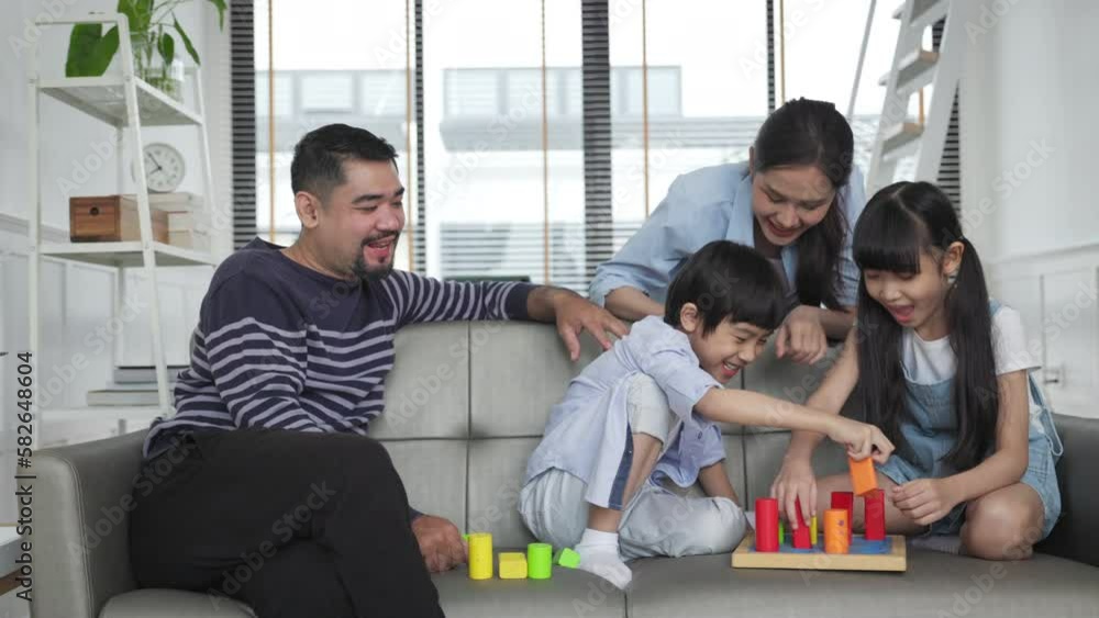 Family relaxing on sofa while kid drawing on floor. Happy Asian little girl enjoy playing a stacking blocks with her parent in living room in free time. Family relaxing on sofa while kid drawing on floor. Happy Asian little girl enjoy playing a stacking blocks with her parent in living room in free time.
