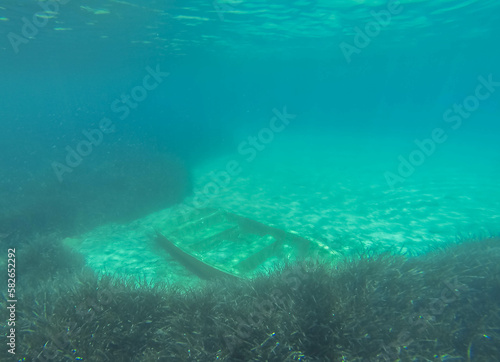 An old boat is abandoned among the algae under the water.