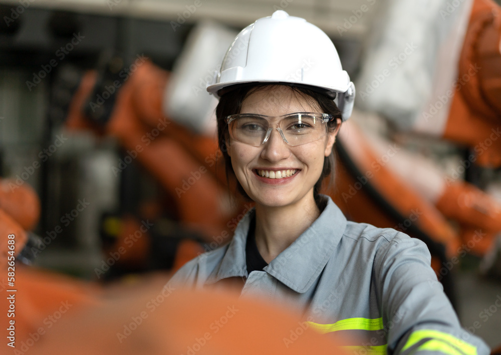 Industrial engineer working on robot maintenance in electronic AI technology factory. Smiling female technician checking automated robotic machine, portrait. Modern woman empowerment in industry 4.0. Industrial engineer working on robot maintenance in electronic AI technology factory. Smiling female technician checking automated robotic machine, portrait. Modern woman empowerment in industry 4.0.