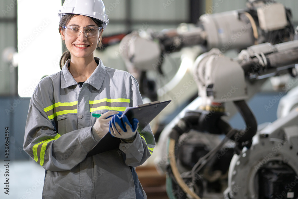 Industrial engineer working on robot maintenance in electronic AI technology factory. Smiling female technician checking automated robotic machine, portrait. Modern woman empowerment in industry 4.0. Industrial engineer working on robot maintenance in electronic AI technology factory. Smiling female technician checking automated robotic machine, portrait. Modern woman empowerment in industry 4.0.
