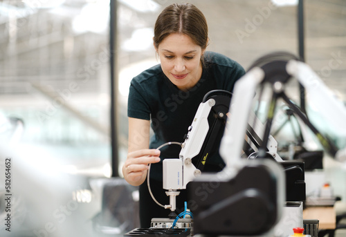 Computer science development engineer working on robotic arm connection at futuristic electronic technology center. Modern people training in industry 4.0 automated engineering. Empowerment woman.