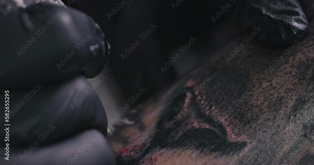 Close up tattoo artist shows the process of getting black tattoos with paint. The master works in black sterile gloves. Master tattoo artist in studio. Close up tattoo artist shows the process of getting black tattoos with paint. The master works in black sterile gloves. Master tattoo artist in studio.