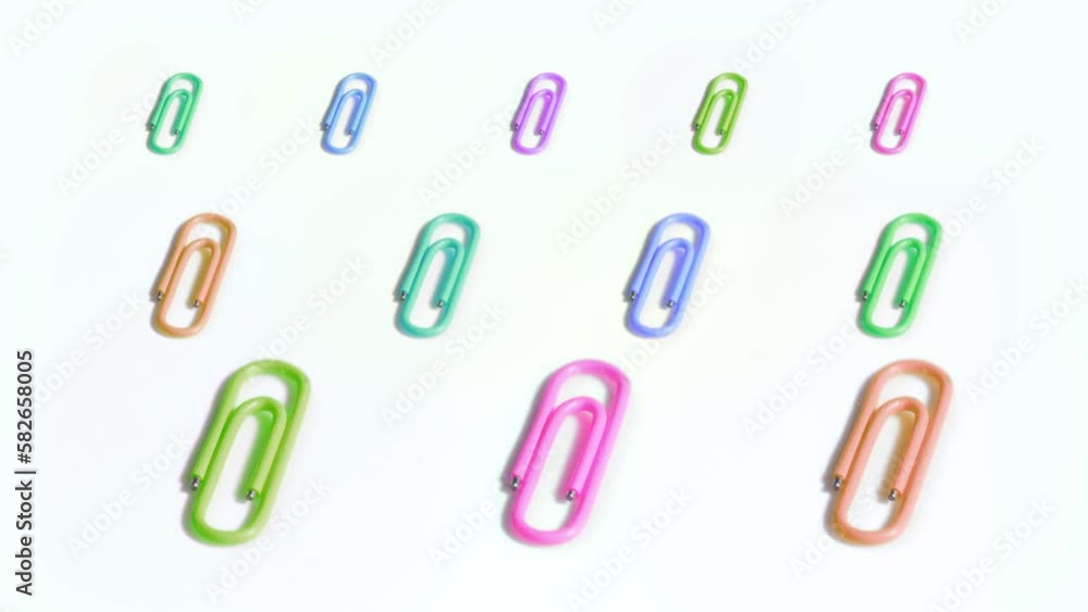 Colorful paper clips are spinning slow on white background Colorful paper clips are spinning slow on white background
