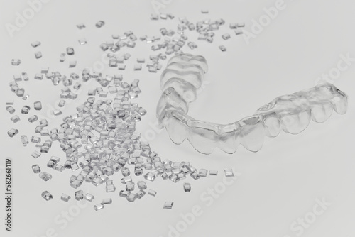 plastic teeth retainer bracket with it's plastic resin granulate on white