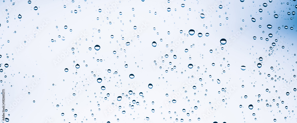 Minimal light backdrop with rain droplets on white glass. Light wet window with rainy drops closeup in blue light. Blurry minimalist monochrome background of window glass with raindrops close up. Minimal light backdrop with rain droplets on white glass. Light wet window with rainy drops closeup in blue light. Blurry minimalist monochrome background of window glass with raindrops close up.
