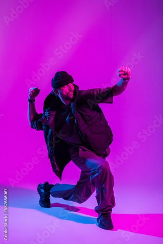 Fashionable professional dancer man in stylish urban clothes dancing in a creative color studio with pink and neon lights © alones