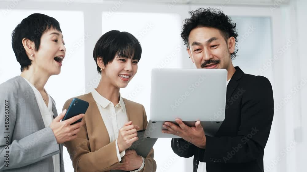パソコンを見ながら話すビジネスパーソンのグループ