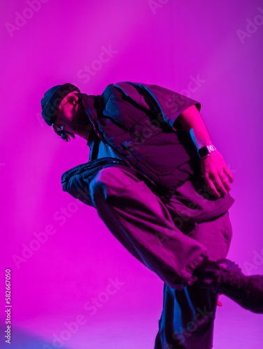 Hipster dancer fashion professional man in fashionable clothes dancing in creative colorful studio with pink and blue light