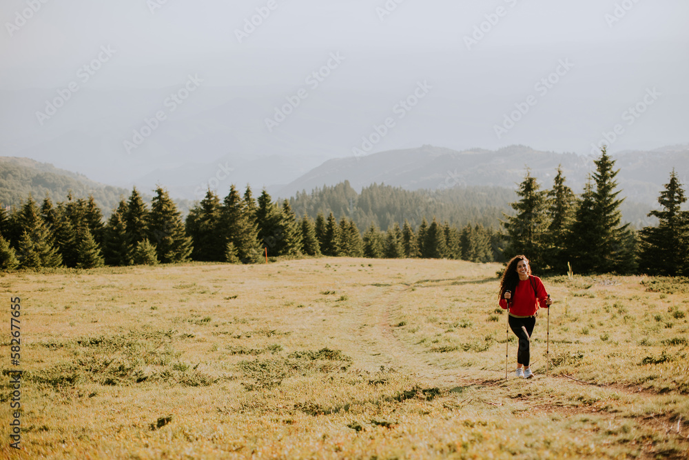 Young woman walking with backpack over green hills
