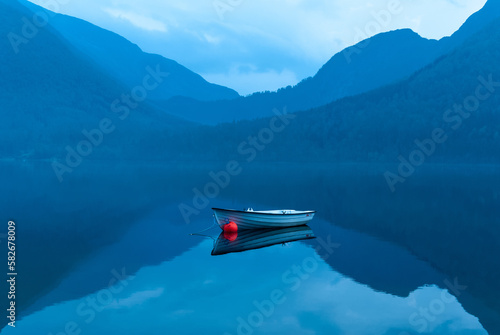 small rowing boat reflects in the water in the blue hour