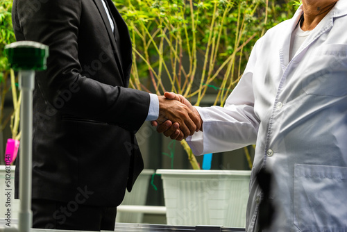 Businessman shaking hands with researcher inside marijuana lab
