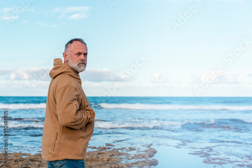Bearded Man relaxing alone on the seaside on hot sunny day at sunset. Travel Lifestyle concept