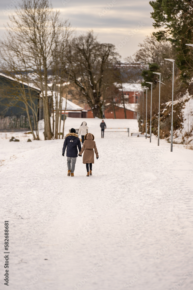 People taking sunday walk in a snowy park.