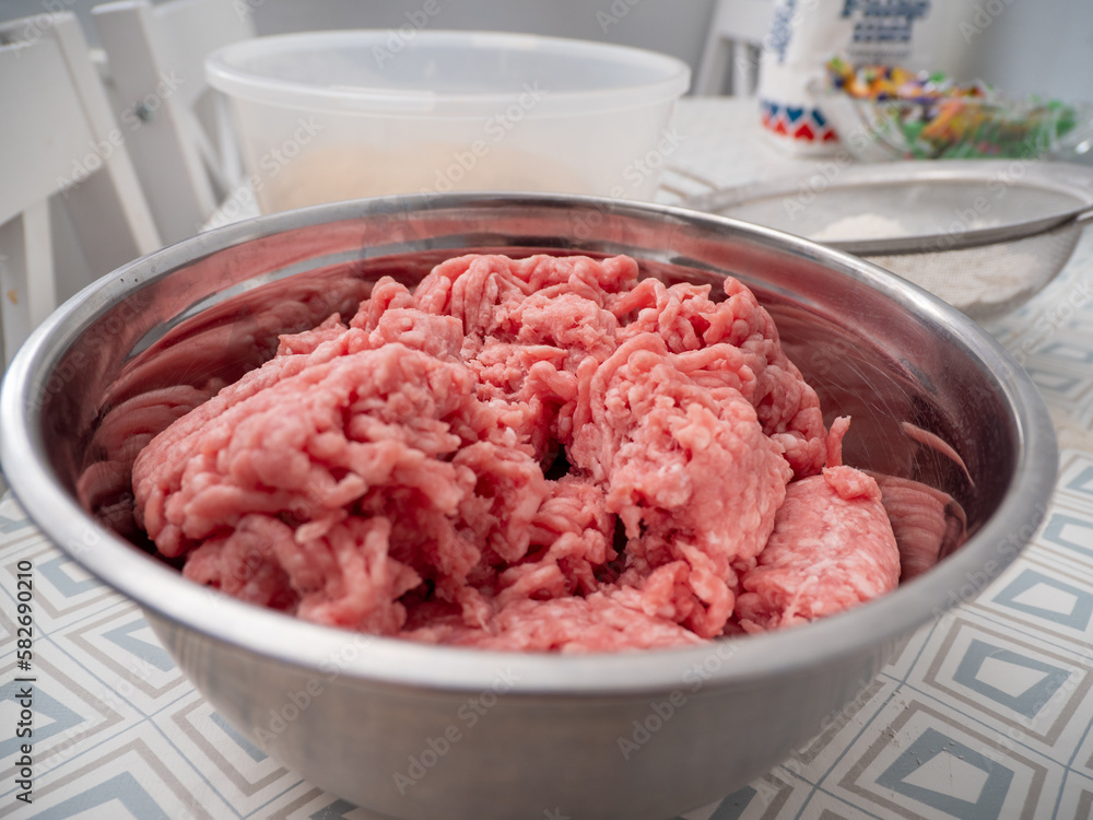 Minced meat in a metal bowl on the kitchen table. Close-up. Minced meat in a metal bowl on the kitchen table. Close-up.