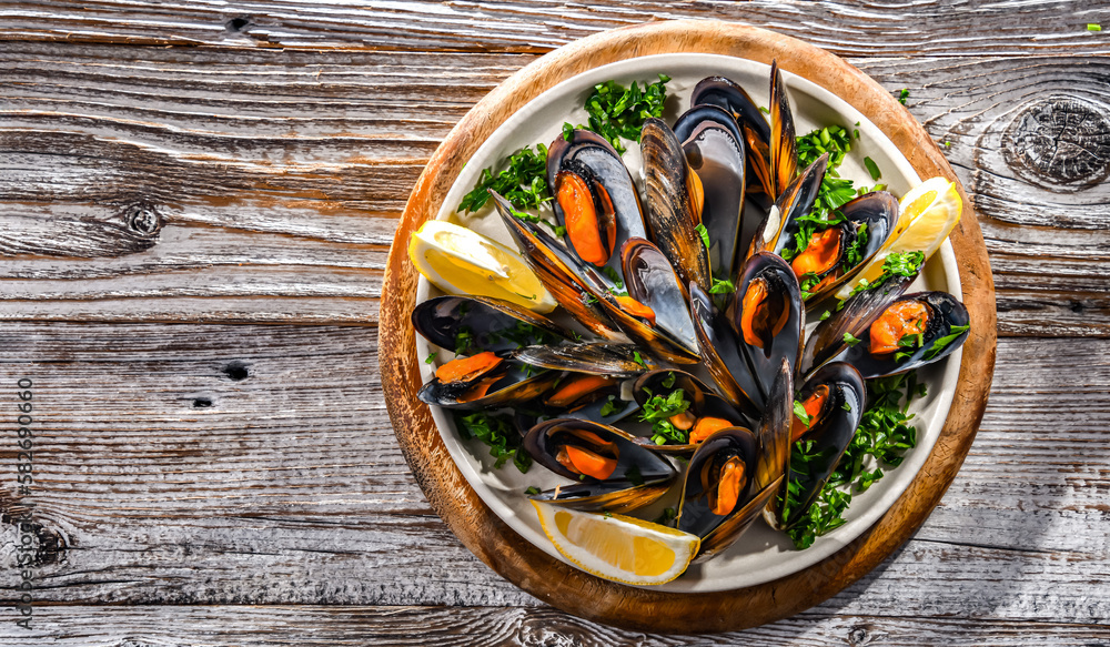 A plate of steamed mussels served with parsley and lemon A plate of steamed mussels served with parsley and lemon