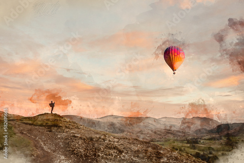 Digital watercolour painting of Wonderful vibrant sunset landscape image of view from Latrigg Fell n Lake District with man photographing hot air ballon in landscape photo