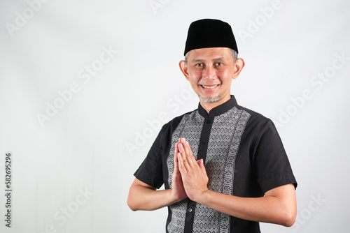 Portrait Asian Moslem Man with greetings and welcoming gestures, smiling face
 photo