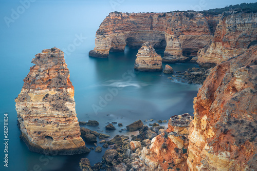 Cliffs, rock formations and natural arches in la Marina beach at sunset in the Algarve region near Albufeira and Portimao cities. Portugal.