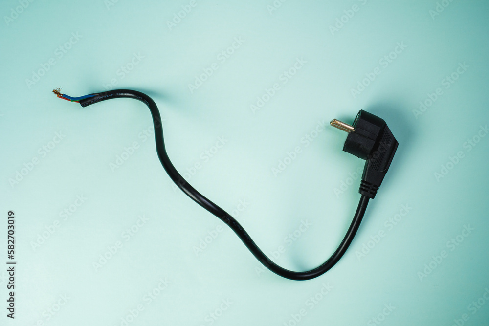 Wire on a light blue background. Copper cable electric stranded wire with black insulation. Curved power cord. Electrical plug Wire on a light blue background. Copper cable electric stranded wire with black insulation. Curved power cord. Electrical plug