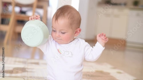 Baby with blue eyes and white t-shirt sit, smile hold plate. Child eating first food. Problems for feeding up children for parents. Heathy and unhealthy ready breakfasts.