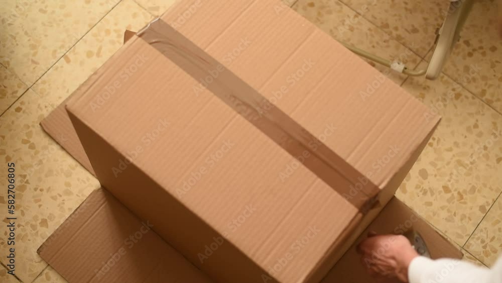 Female hands with adhesive tape fixes bottom of cardboard box. Box for packing all stuff and goods. Moving from house to house - big problem for people. Female hands with adhesive tape fixes bottom of cardboard box. Box for packing all stuff and goods. Moving from house to house - big problem for people.