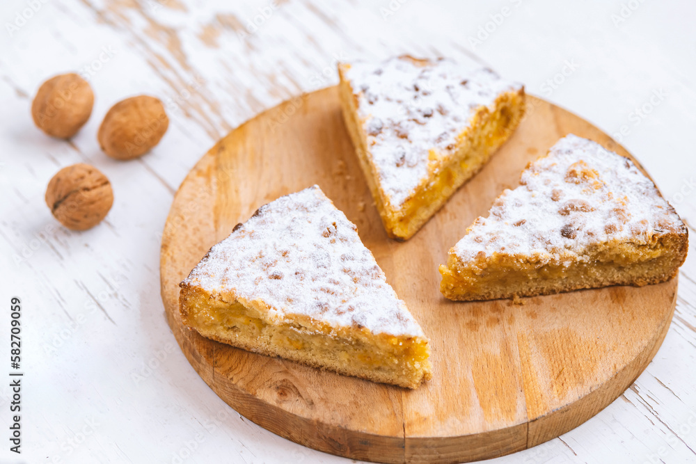 Pieces of apple pie with walnuts on wooden background