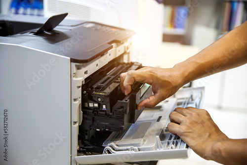 Technician hand open cover printer photocopier or photocopy to replace ink cartridges or fix paper jam for scanning fax or copy document in office workplace. photo