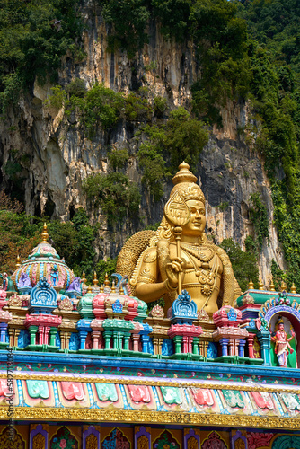 A huge golden statue of Lord Murugan at the entrance with multicolored steps to the Batu Caves