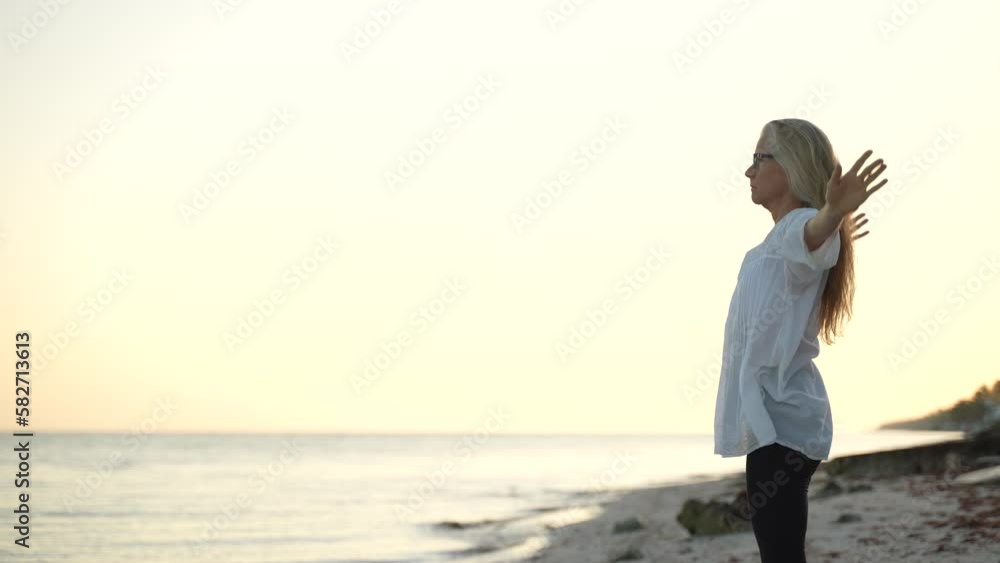 Fit mature senior woman stretching practicing yoga and dancing during the morning sunrise on the beach. Fit mature senior woman stretching practicing yoga and dancing during the morning sunrise on the beach.