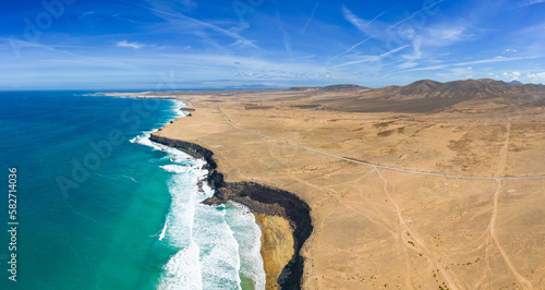 Aerial high level panoramic view of the rocky cliffs and beaches with the volcanic mountain backdrop near El Cotillo in Fuerteventura Spain
