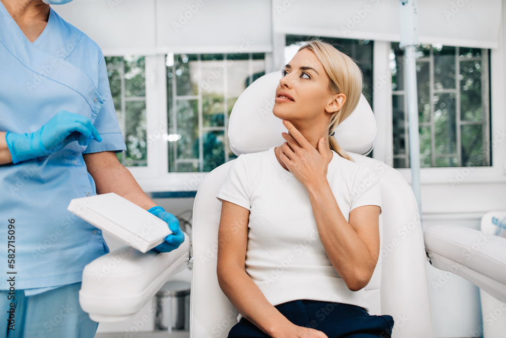 Beautiful and happy blonde woman at beauty medical clinic. She is sitting and talking with female doctor about face aesthetic treatment. Beautiful and happy blonde woman at beauty medical clinic. She is sitting and talking with female doctor about face aesthetic treatment.
