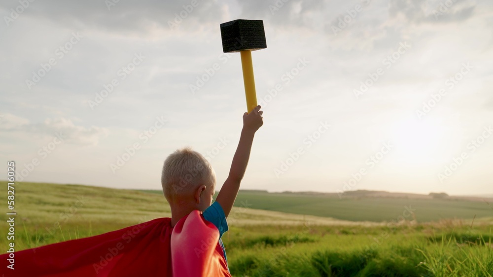 Child plays superhero from comic book, child holds hammer in his hand