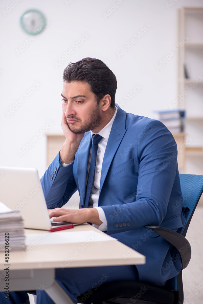 Young male employee and too much work in the office