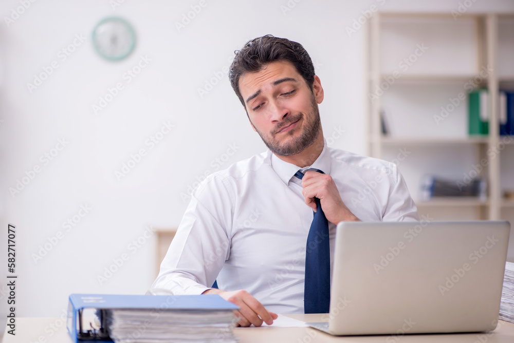 Young male employee and too much work in the office Young male employee and too much work in the office