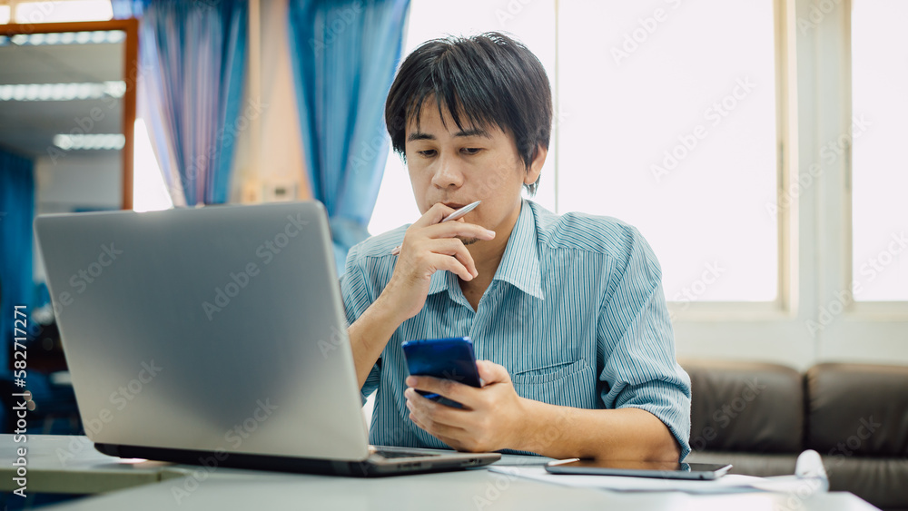 businessman using smart phone while working on a laptop in a coworking space home office