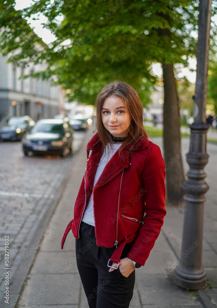 Beautiful Young Girl is Standing on the side Walk in Vilnius Old Town, Lithuania. Wearing Red jacket and Black Trousers. Beautiful Spring Day Beautiful Young Girl is Standing on the side Walk in Vilnius Old Town, Lithuania. Wearing Red jacket and Black Trousers. Beautiful Spring Day