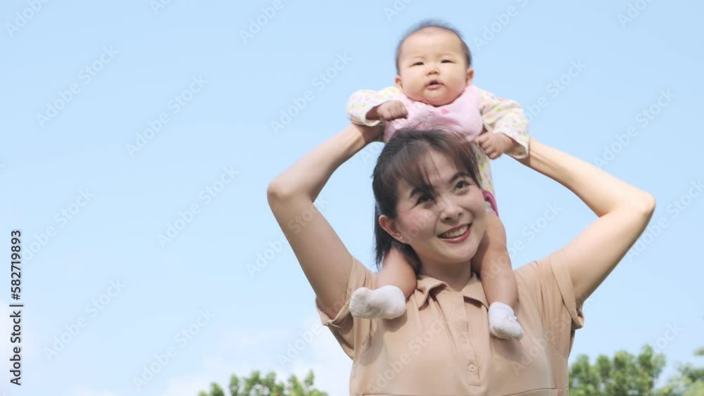 Beautiful asian mother gives her cute little daughter ride on her neck and playful in the garden. Beautiful asian mother gives her cute little daughter ride on her neck and playful in the garden.