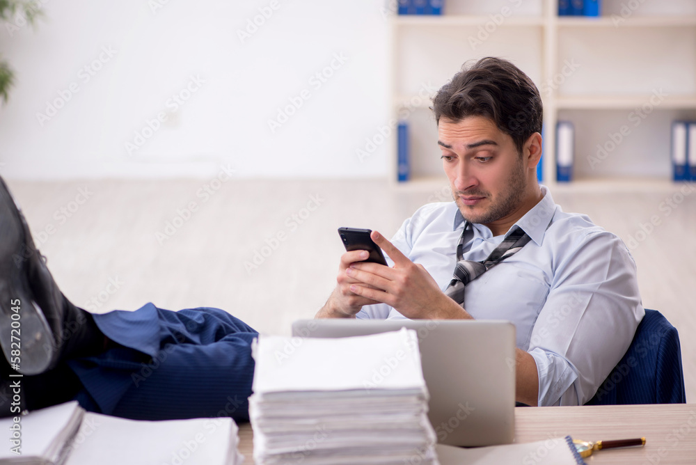 Young male employee and too much work in the office Young male employee and too much work in the office