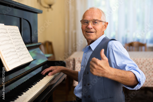 Elderly composer composes music and plays piano at home
