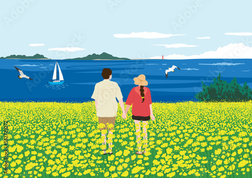 A happy couple looking at the sea from the yellow rape flower field