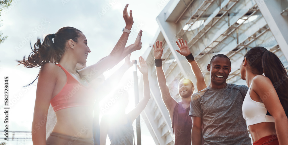 © gstockstudio - Group of happy young people in sports clothing giving high five while standing outdoors together